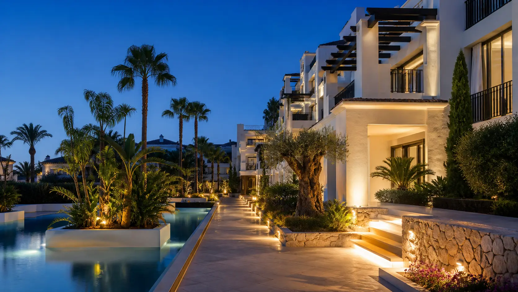 Comunidad residencial de la Costa del Sol iluminada al anochecer junto a la piscina